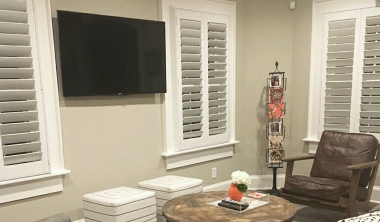 Evergreen window treatments are energy-efficient and have a long lasting appeal. Plantation shutters in a sitting room